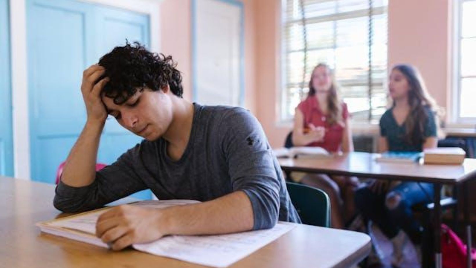 A stressed boy sitting in school and reading