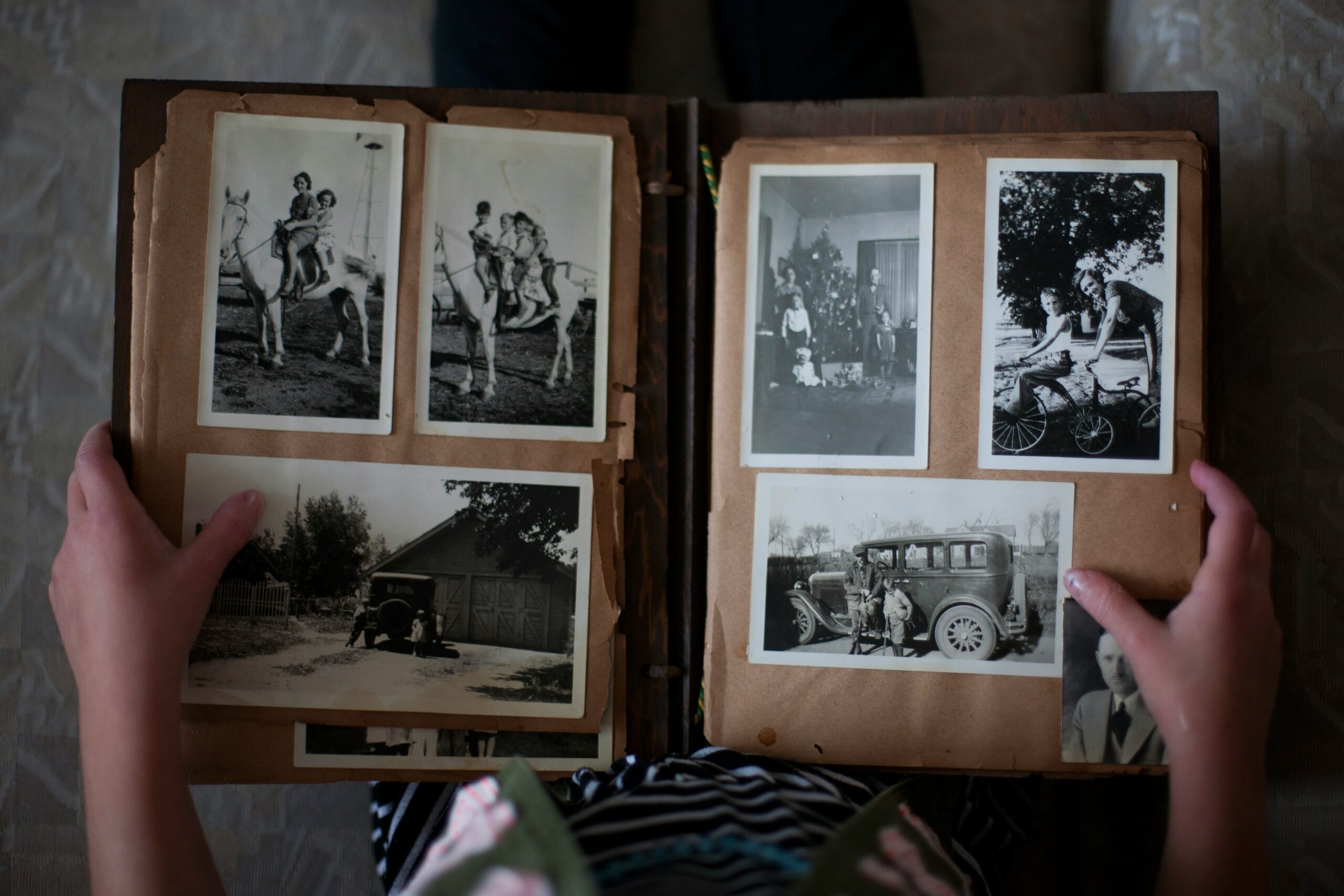 Hands holding an old photo album with vintage family photographs.