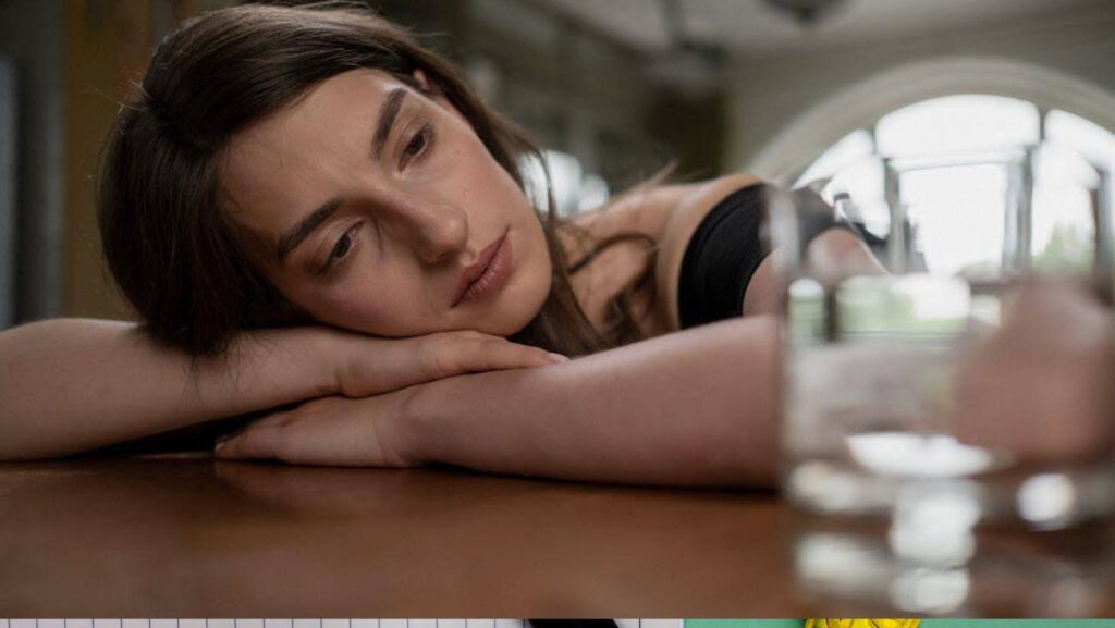 Sad woman looking at a glass on the table.